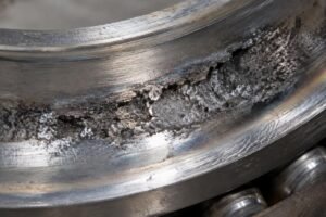 Close-up view of spalled raceway in a failed wind turbine hybrid bearing showing surface fatigue
